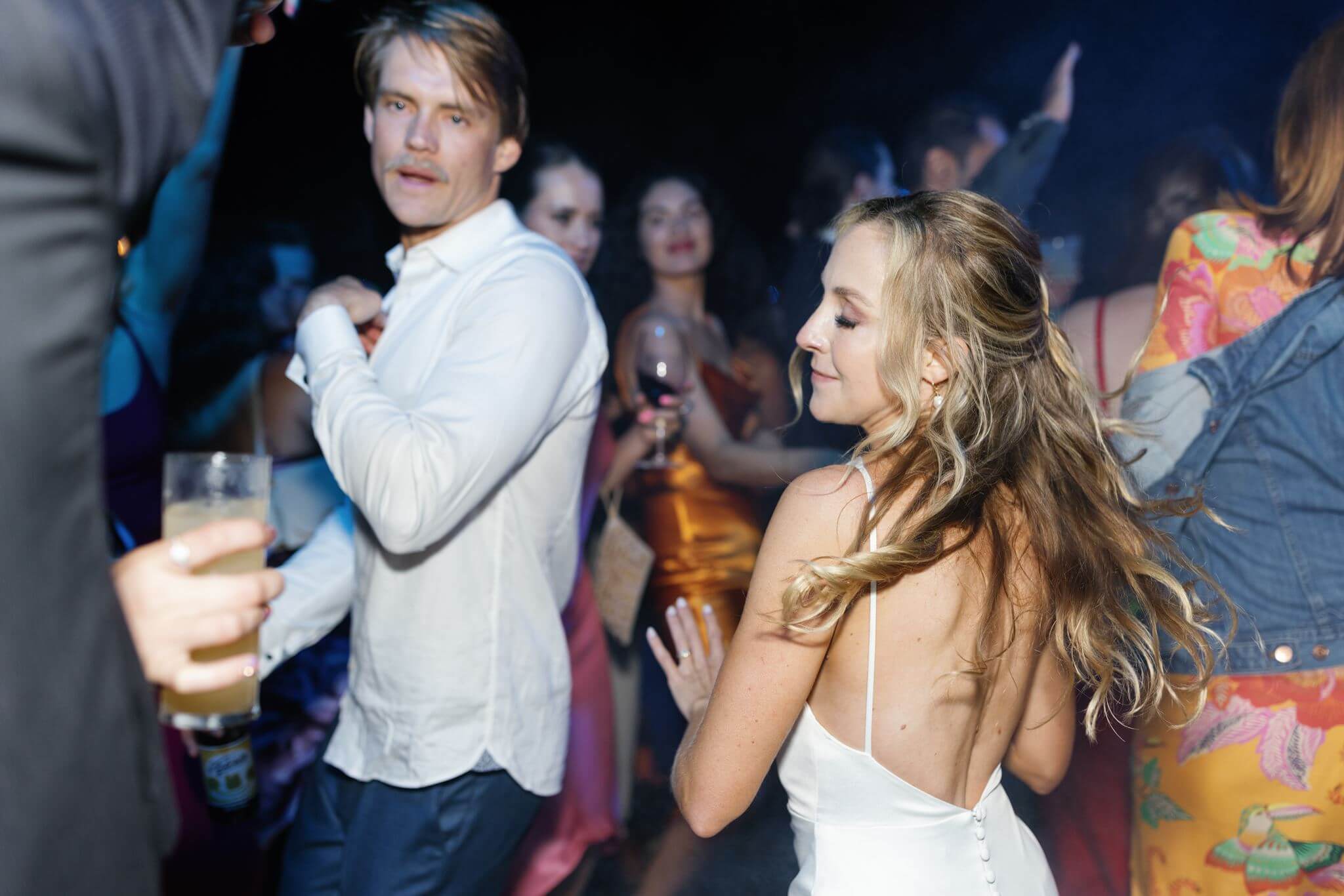 Bride smiling on the dance floor while surrounded by wedding guests.