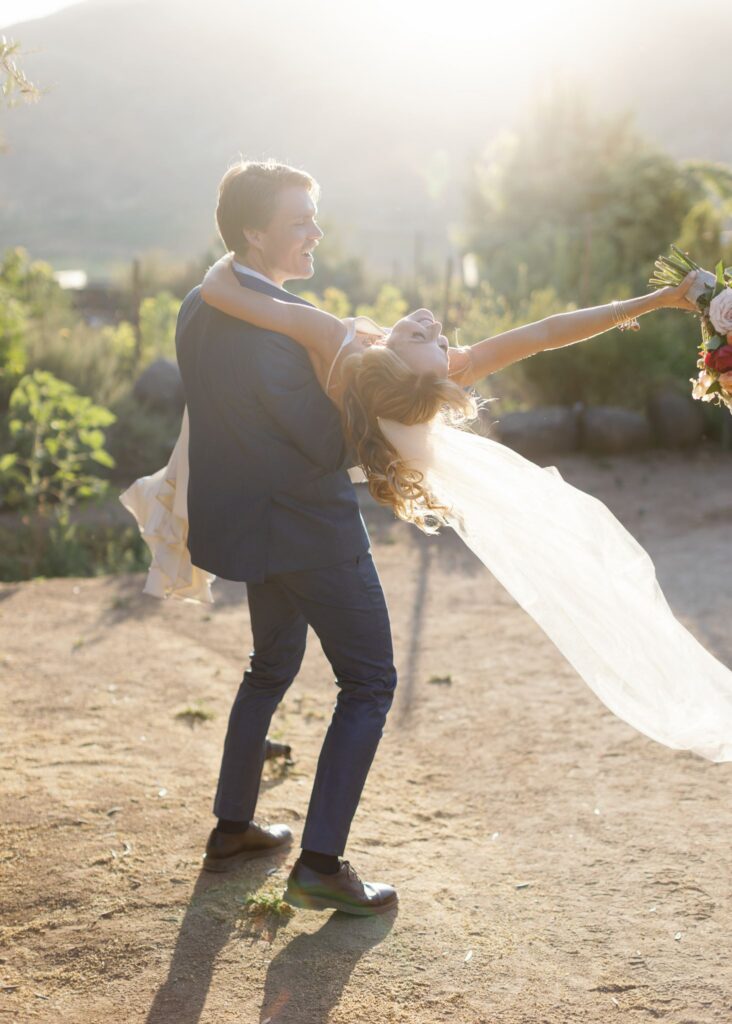 Groom dipping the bride during playful golden-hour wedding portraits at Bruma Valle de Guadalupe.