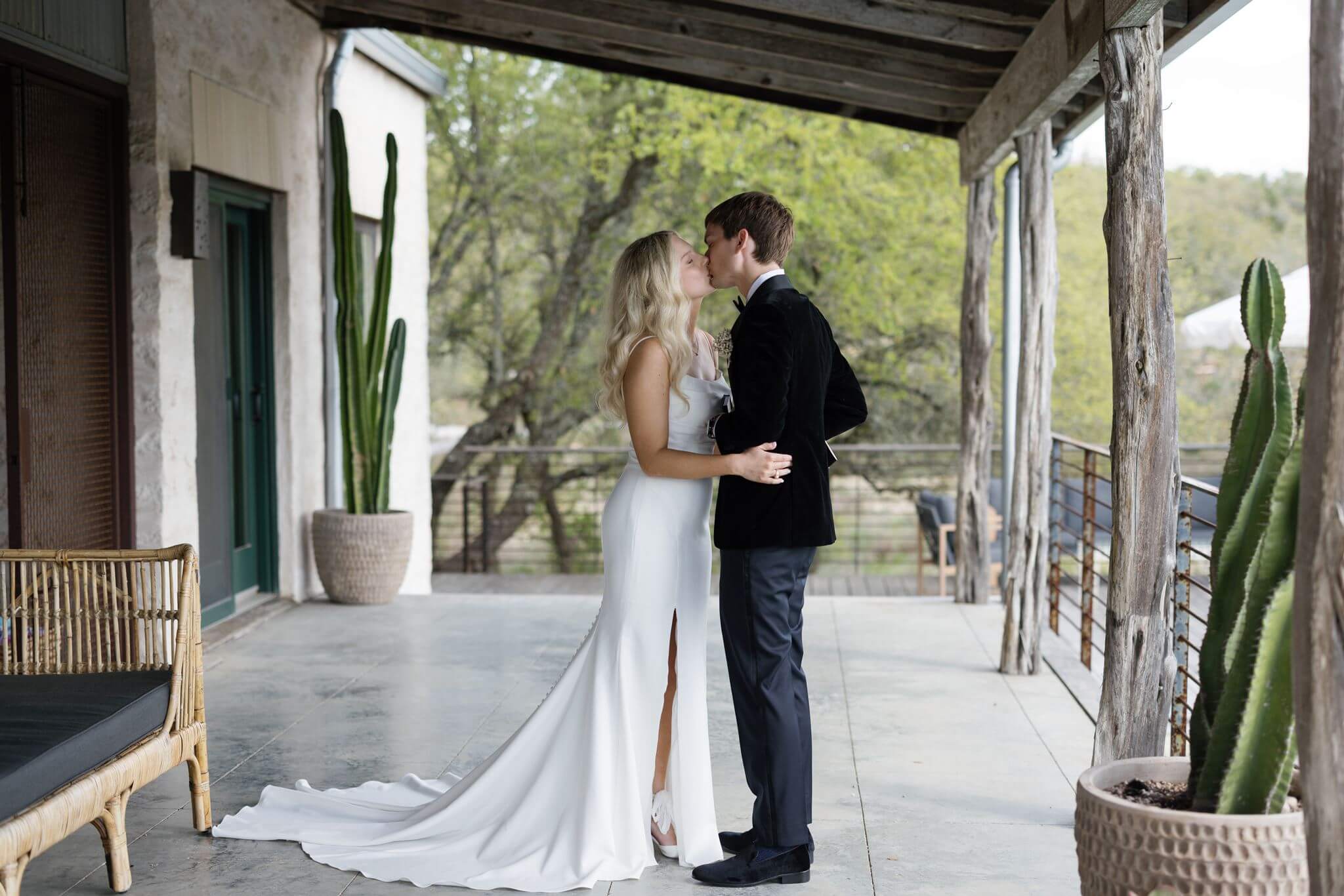 Bride and groom sharing a kiss on the covered patio of the wedding venue