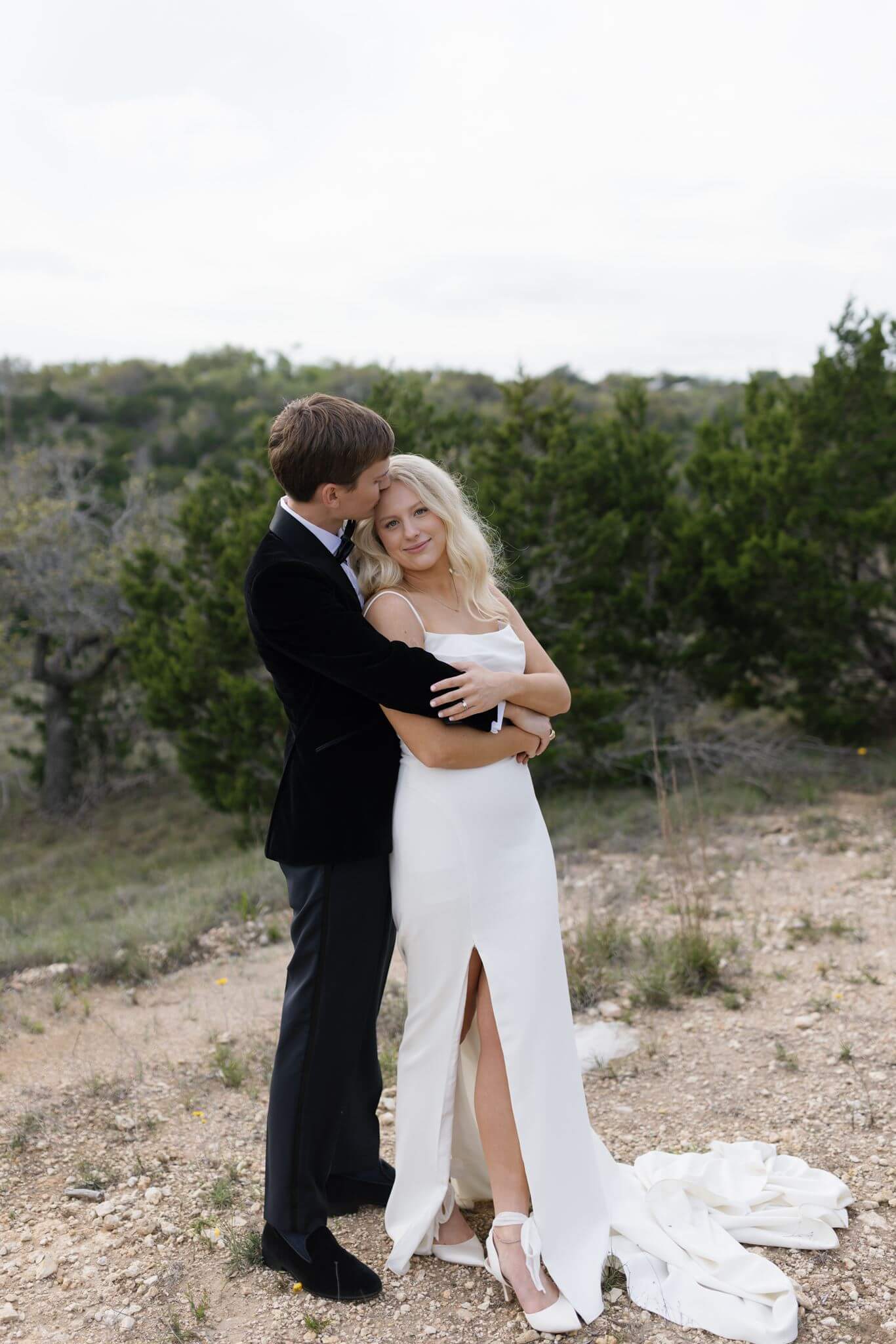 Bride and groom sharing a close embrace outdoors in the hill country