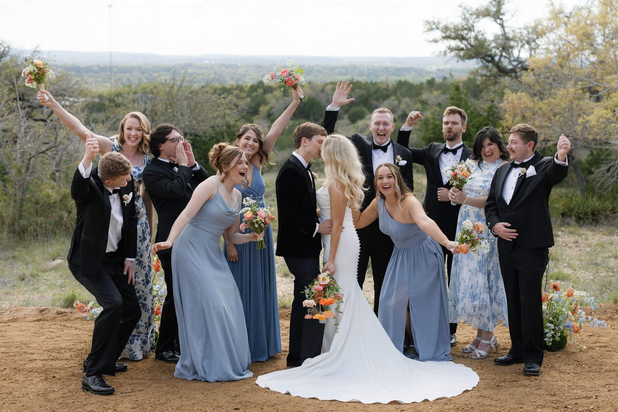 Wedding party cheering and celebrating with the bride and groom on the hillside overlooking the Texas Hill Country