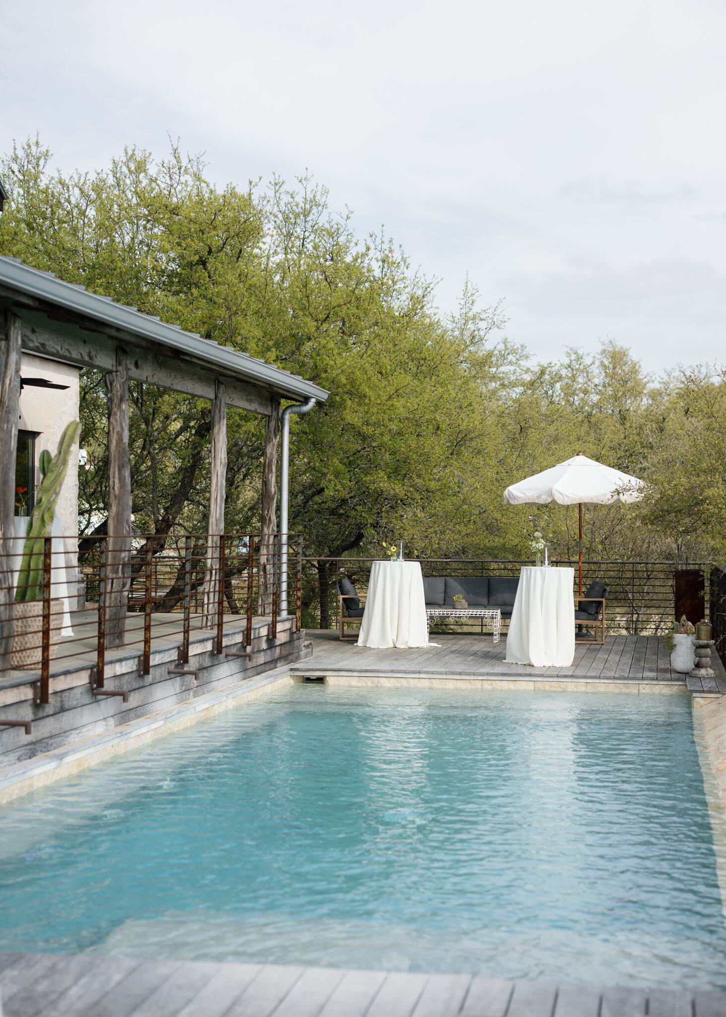 Outdoor swimming pool with lounge seating and a white umbrella at a Texas Hill Country wedding venue