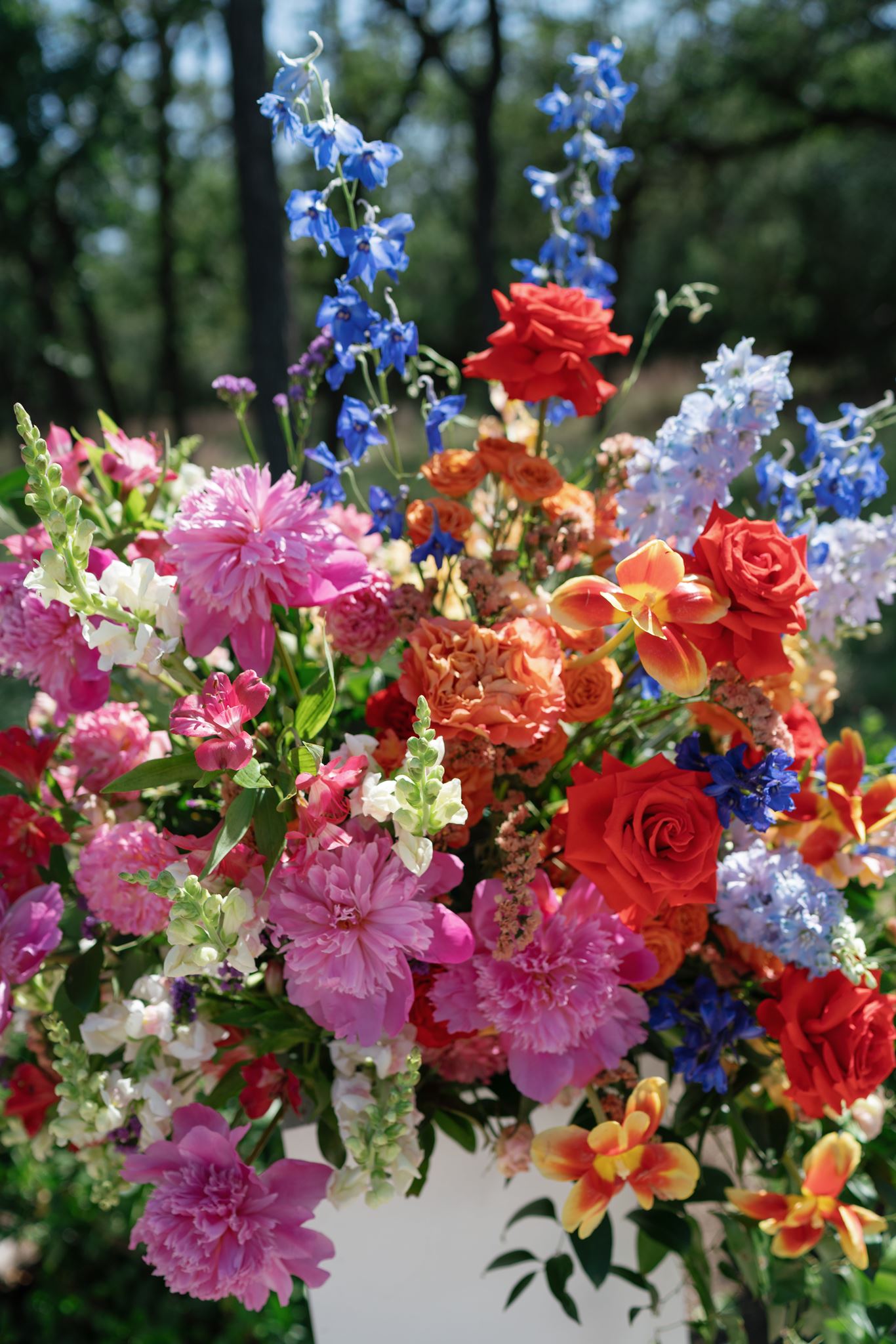 Close-up of a vibrant wedding arrangement filled with pink, red, orange, blue, and purple flowers.