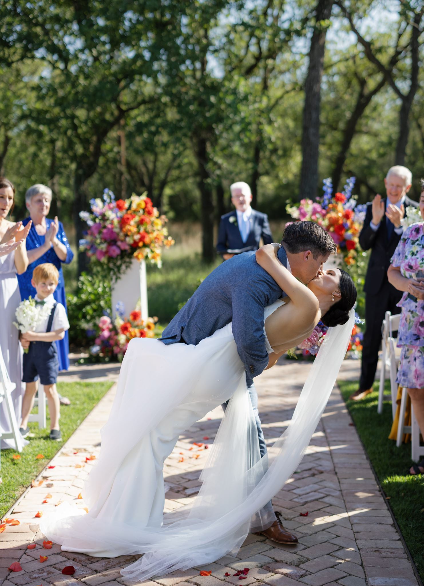 Bride and groom sharing a dramatic dip kiss in the aisle immediately after their ceremony.