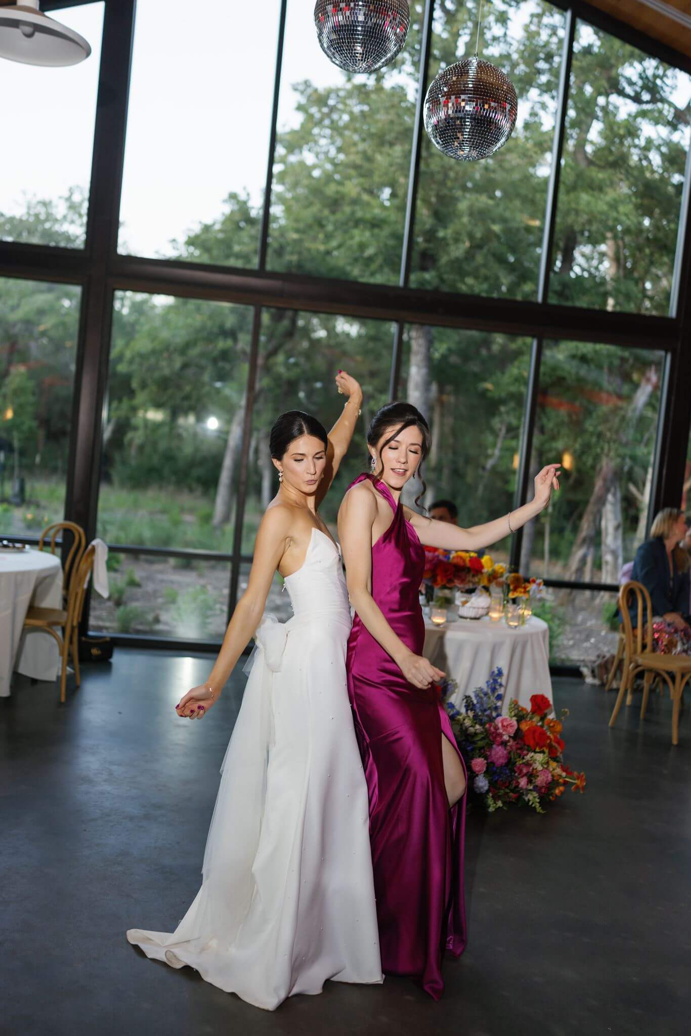 Bride dances with a wedding guest in a magenta dress beneath disco balls during the reception at The Grand Lady in Austin.