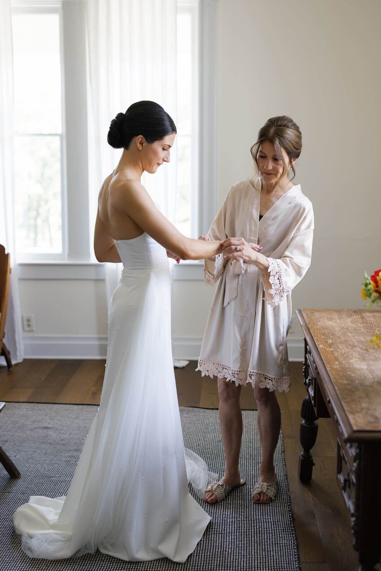 Mother helping a bride put on a bracelet while she's getting ready