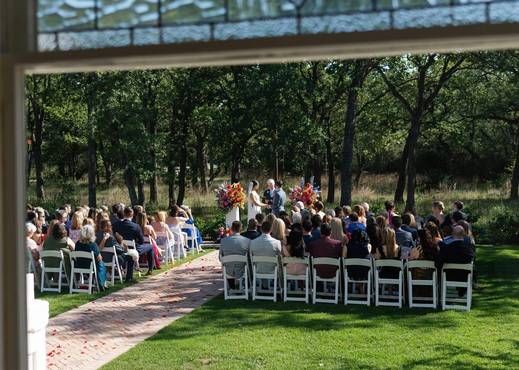 Wide shot out a window of a bride and groom during their wedding ceremony